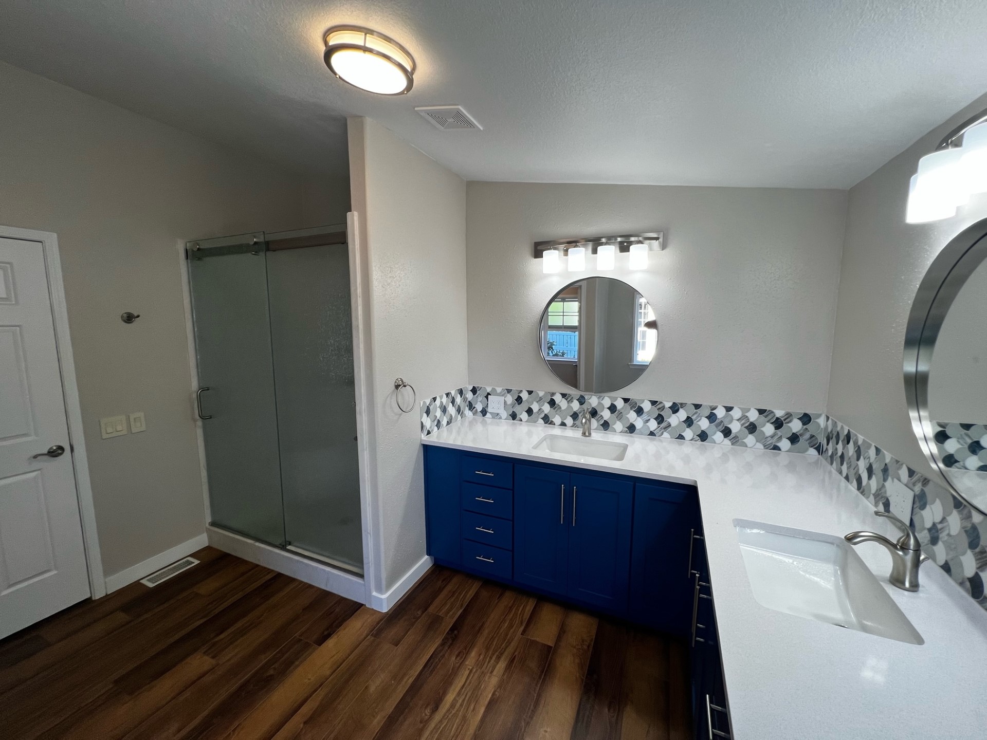 A bright finished bathroom with blue vanity, mirror and natural light
